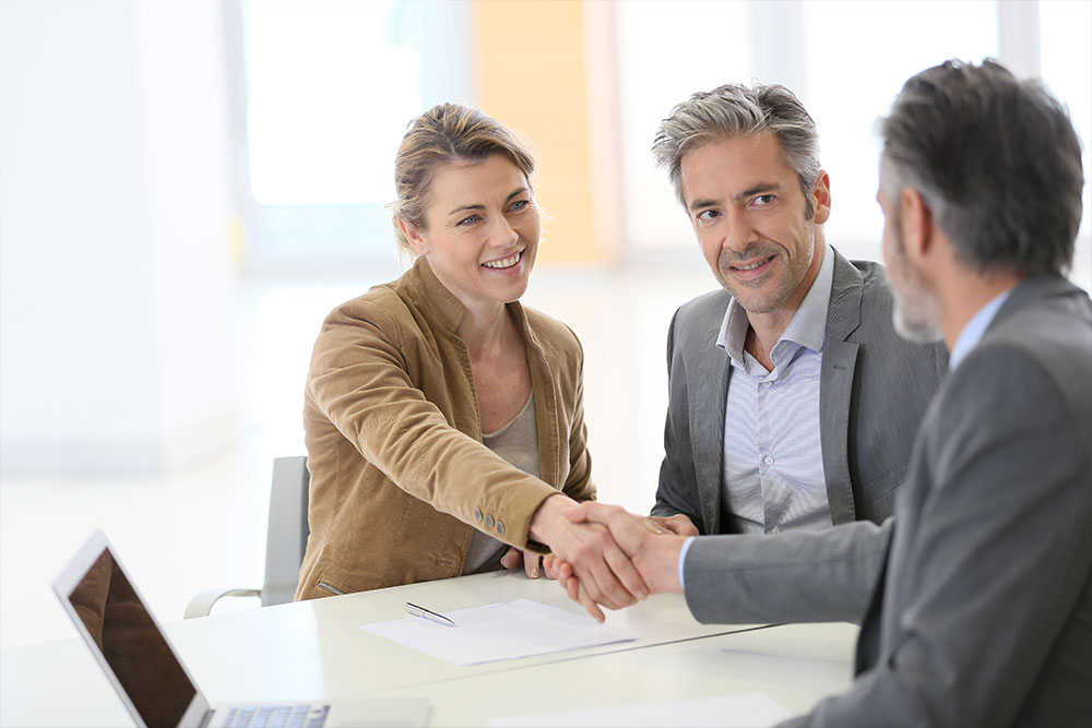 Two people shaking hands across a desk