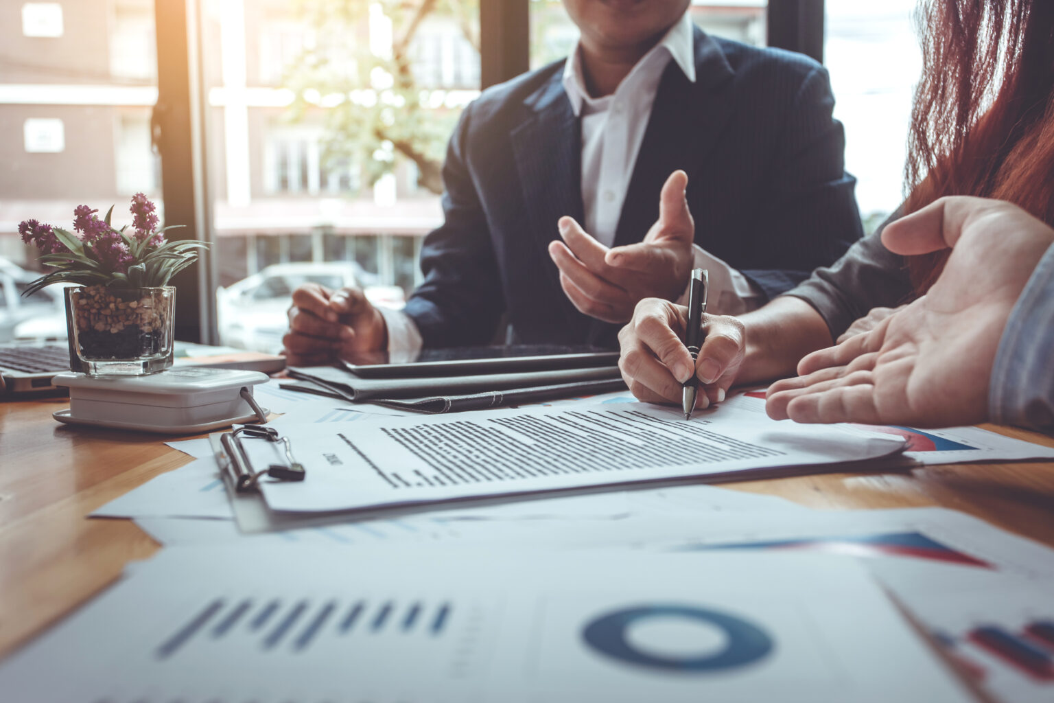 A business meeting with people reviewing charts and reports on a table